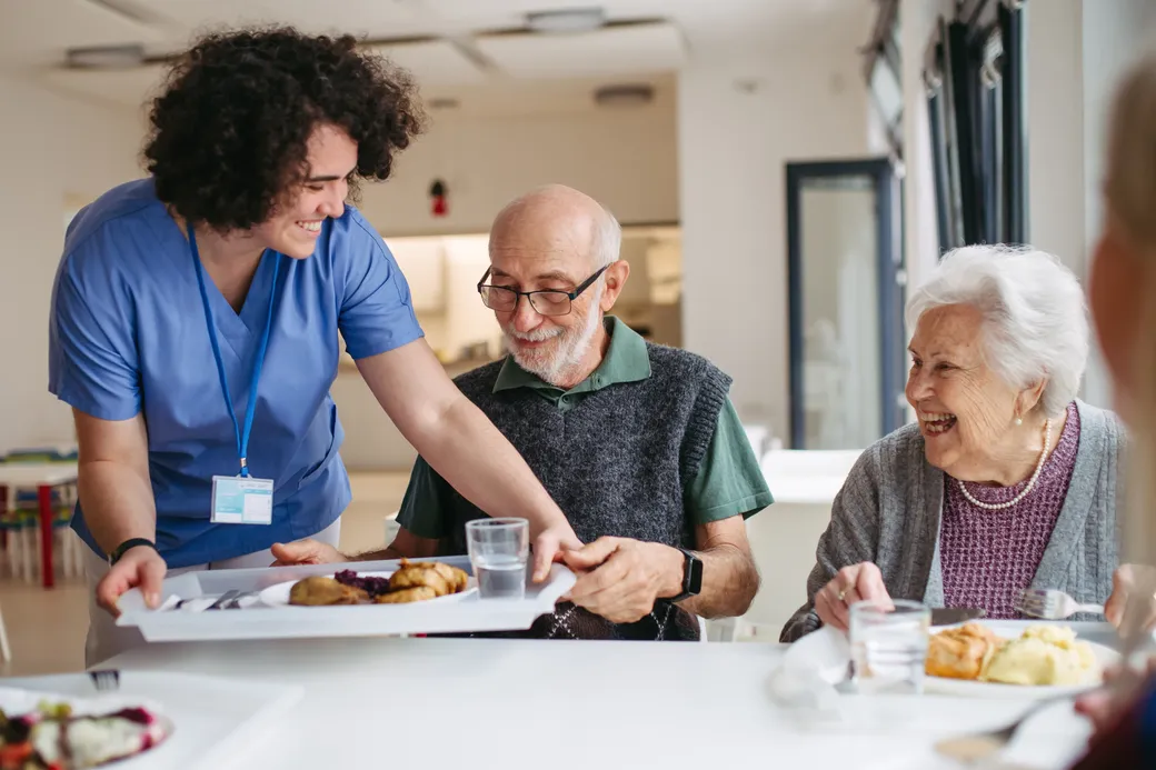 A care worker serving lunch to residents